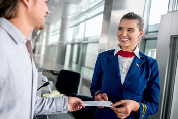 junge Frau am Check-in nimmt Flugticket entgegen