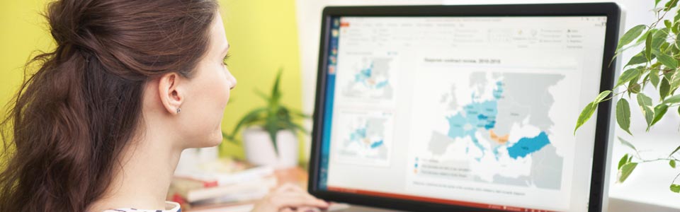 Junge Frau, die vor Computerbildschirm mit geöffneter Weltkarte sitzt.